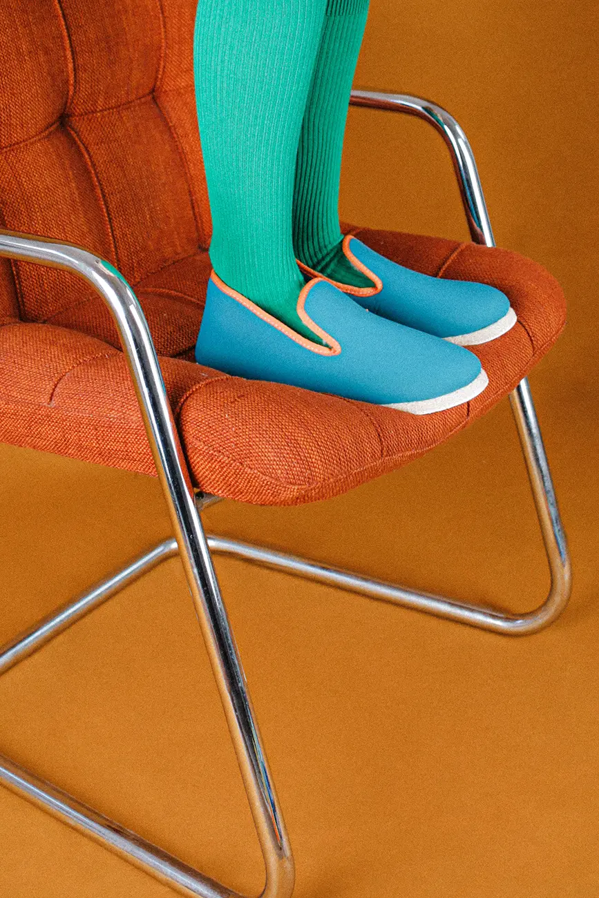 Debout sur une chaise orange en chaussons bleu